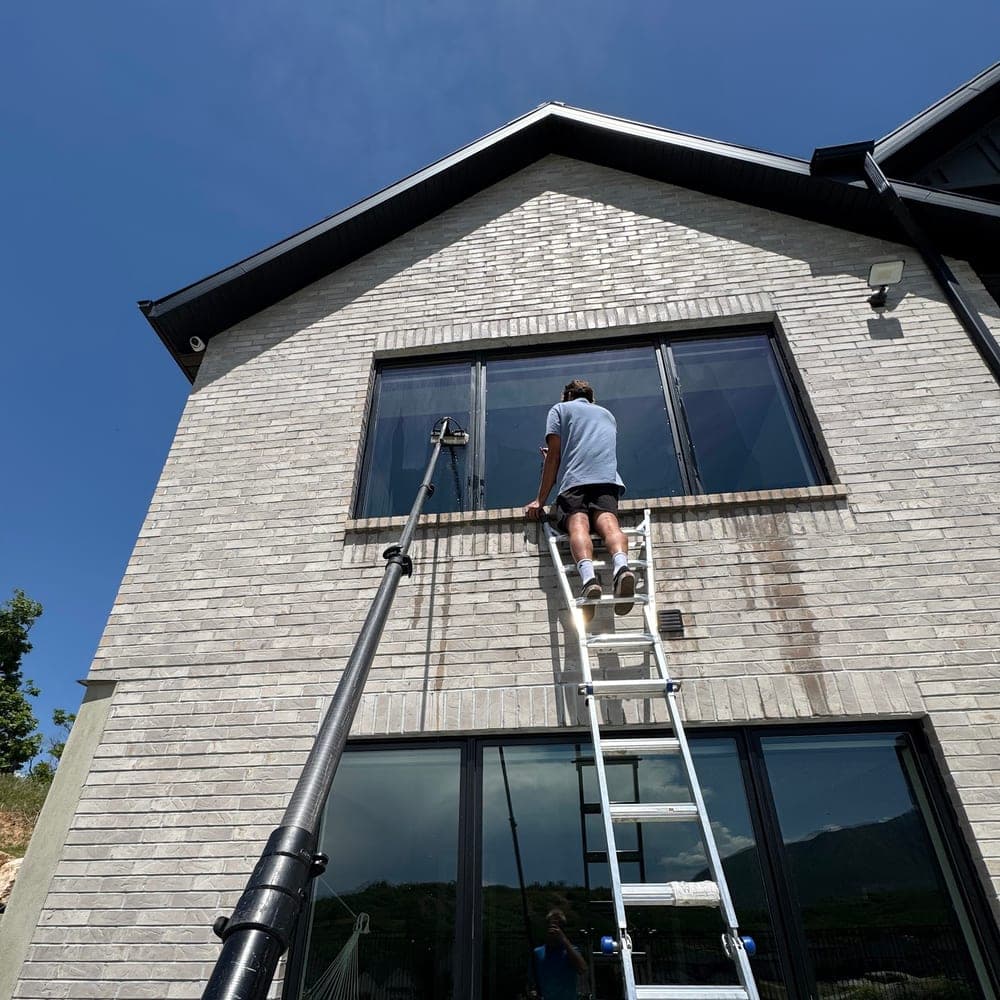 Technician on a ladder cleaning upper windows