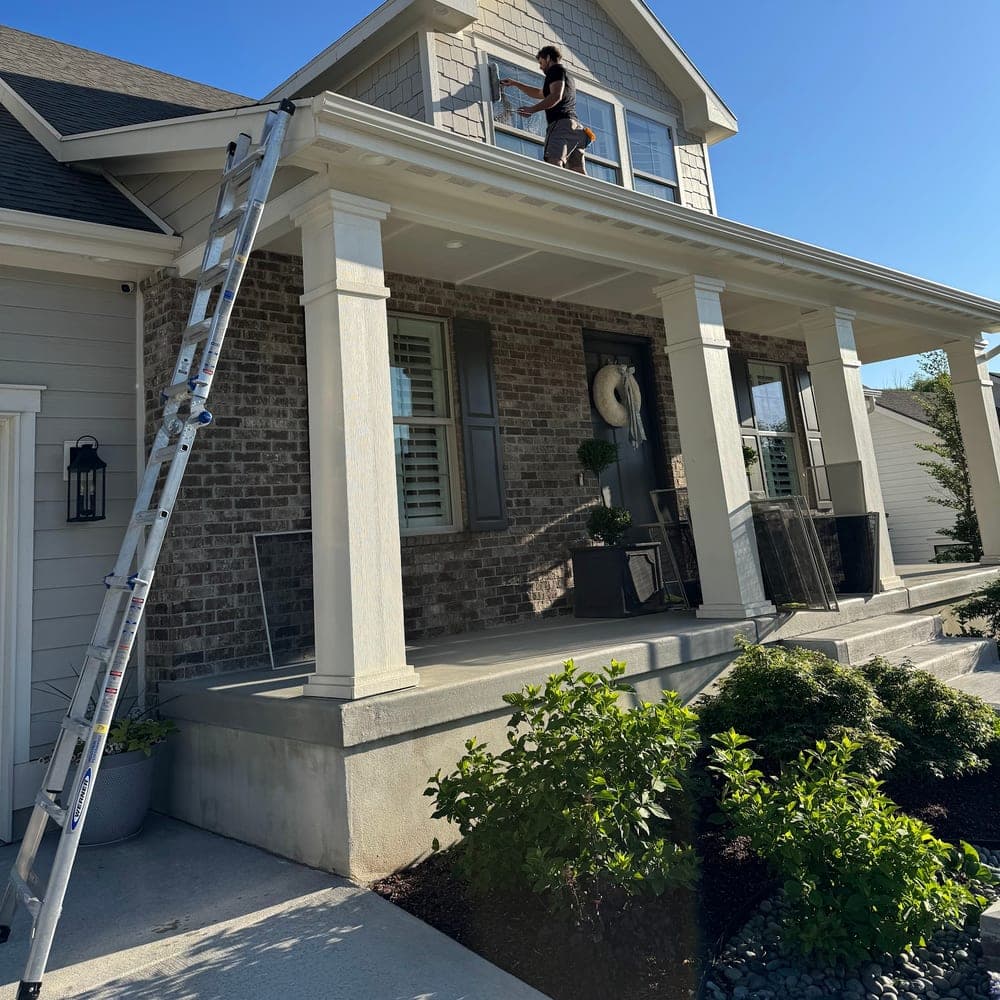 Technician on an extension ladder washing second-story windows